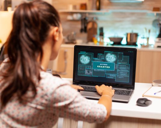 Hacker woman launching a cyberattack on bank firewall from home during night time. Programmer writing a dangerous malware for cyber attacks using performance laptop during midnight.